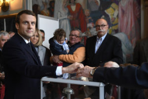 French presidential election candidate for the En Marche ! movement Emmanuel Macron (L) casts his ballot at a polling station in Le Touquet, northern France, on April 23, 2017, during the first round of the Presidential election. / AFP PHOTO / POOL / Eric FEFERBERG